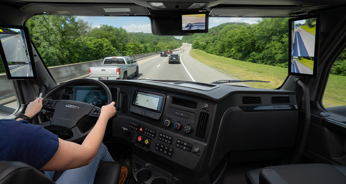 Freightliner truck dashboard and windshield view showing highway driving perspective and digital controls